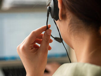 woman wearing earpiece to conduct phone interview sitting in front of laptop